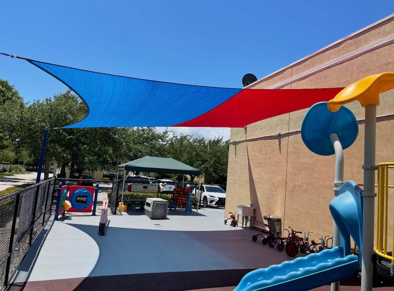 Blue and red commercial shade sails covering a childcare playground in South Florida