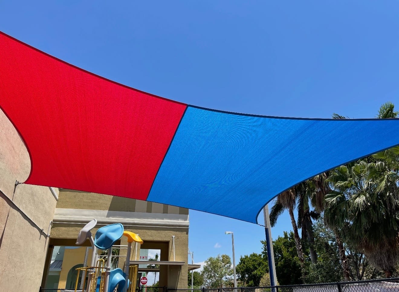 Red and blue tensioned shade sails over a daycare play area installed by EAB Awnings