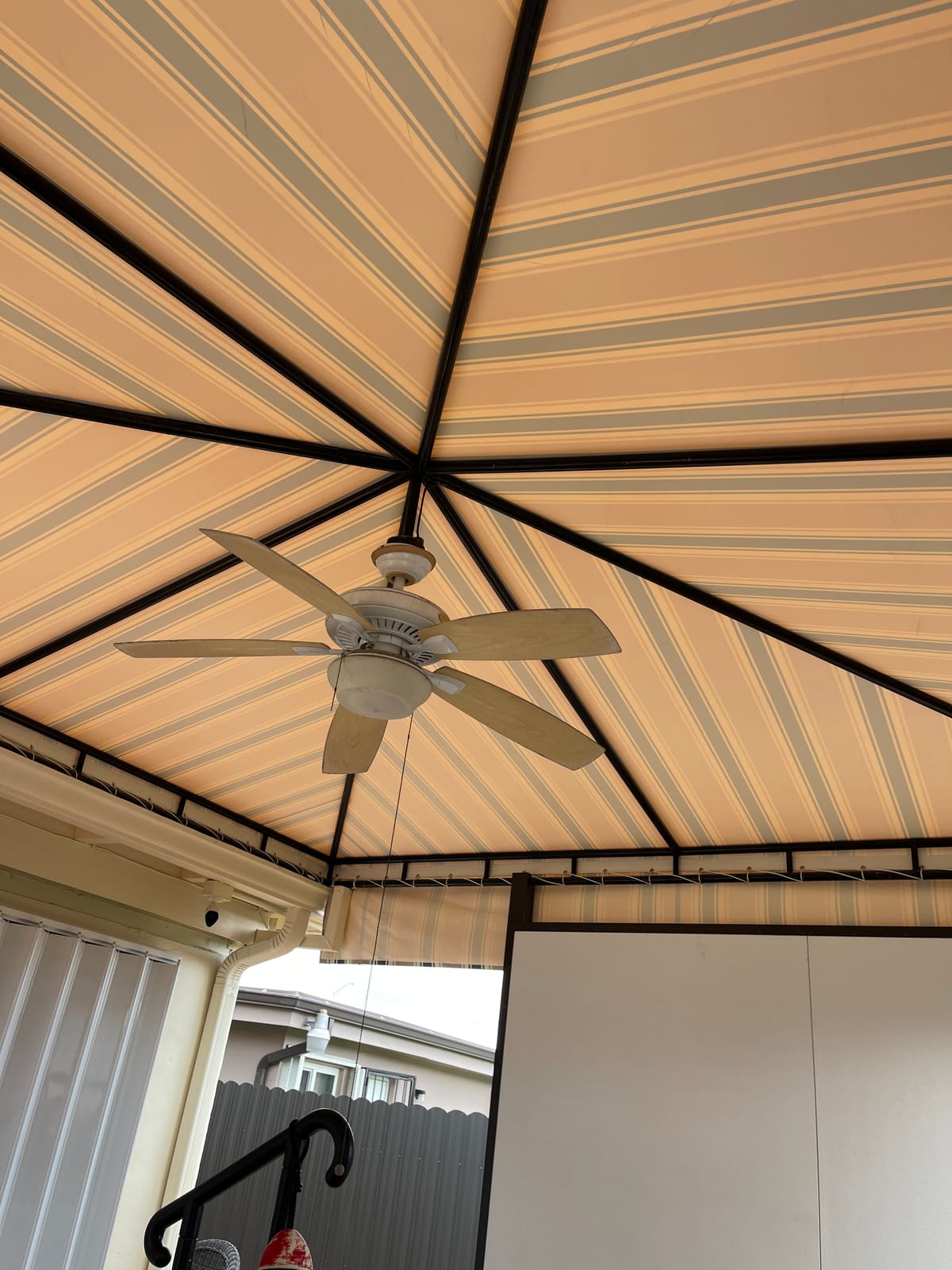 Underside of a striped canvas gazebo canopy with an integrated ceiling fan